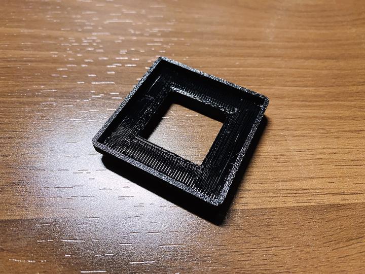 Photo of a 3D printed fan mount as a simple 40 mm slab with a 20 mm wall extruding from it