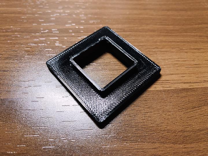 Photo of a 3D printed fan mount as a simple 40 mm slab with a 20 mm hole in a middle of it